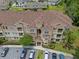 Aerial view of a tan condo building with a brown roof and parking in front and mature landscaping at 621 Terrace Ridge Cir # 621, Davenport, FL 33896
