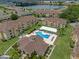 Aerial view of a community clubhouse and blue pool with lounge chairs and umbrella, and other buildings around it at 621 Terrace Ridge Cir # 621, Davenport, FL 33896