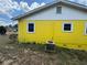 Back exterior featuring yellow siding and updated white trim windows on a sunny day at 825 Poinsettia Dr, Eustis, FL 32726