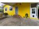 View of the house with yellow siding, a covered area and brick steps leading up to the front door at 825 Poinsettia Dr, Eustis, FL 32726