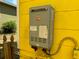 Exterior shot of an on-demand water heater on the yellow-painted side of a house at 825 Poinsettia Dr, Eustis, FL 32726