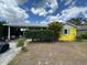 Charming home featuring a carport, yellow siding, and a nicely trimmed privacy hedge at 825 Poinsettia Dr, Eustis, FL 32726
