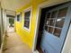 View of the covered front porch with yellow walls and blue door at 825 Poinsettia Dr, Eustis, FL 32726