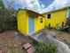 Exterior view of a yellow storage shed with a blue door at 825 Poinsettia Dr, Eustis, FL 32726