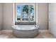 Relaxing bathroom featuring a tiled soaking tub with large windows offering serene water views at 9916 Lone Tree Ln, Orlando, FL 32836