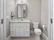 Bathroom with white vanity, granite counters, toilet, tile floors, a large mirror, and a window at 9916 Lone Tree Ln, Orlando, FL 32836