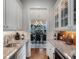 Butler's pantry with granite counters, white cabinets, backsplash, and view of dining room at 9916 Lone Tree Ln, Orlando, FL 32836