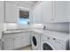 Bright laundry room featuring a washer and dryer with custom cabinets and granite countertops at 9916 Lone Tree Ln, Orlando, FL 32836