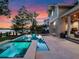Beautiful backyard with a sparkling pool and lush landscaping, offering stunning waterfront views at twilight at 9916 Lone Tree Ln, Orlando, FL 32836