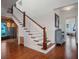 View of staircase featuring wood and white railings, hardwood floors, lower storage area, and glass-enclosed wine storage at 9916 Lone Tree Ln, Orlando, FL 32836