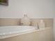 Close-up of bathtub with tan tile surround and modern chrome faucet at 10371 Kensington Shore Dr # H-201, Orlando, FL 32827