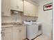 Functional laundry room featuring a sink, cabinets, granite countertops, and modern washer and dryer at 10371 Kensington Shore Dr # H-201, Orlando, FL 32827