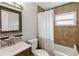 The bathroom features decorative tile accent, vanity with sink, tub, and window at 10934 Tangora St, Orlando, FL 32825