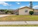 Single-story home with tan siding and manicured lawn in a sunny day with partial stone facade and a well manicured front yard at 10934 Tangora St, Orlando, FL 32825