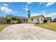 Charming single-story home with a circular driveway and well-maintained landscaping under a bright, cloudy sky at 10934 Tangora St, Orlando, FL 32825