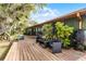 Backyard deck with seating and lush landscaping attached to a green home with dark trim and many windows at 1200 Auger Dr, New Smyrna Beach, FL 32168