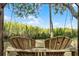 A wood backyard swing with two seats and a view of native marsh vegetation and blue sky on a sunny day at 1200 Auger Dr, New Smyrna Beach, FL 32168