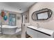 Bright bathroom with a freestanding tub, decorative lanterns, and a modern white vanity with a gray framed mirror at 1200 Auger Dr, New Smyrna Beach, FL 32168