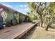 Inviting wooden deck perfect for outdoor entertaining with mature trees and lush tropical landscaping all around at 1200 Auger Dr, New Smyrna Beach, FL 32168