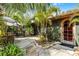 Charming home featuring a wooden arched doorway, lush landscaping, and a cozy patio area for relaxation at 1200 Auger Dr, New Smyrna Beach, FL 32168