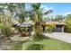 Charming single-story home featuring a lush, tropical landscaped yard and patio area with stylish umbrella at 1200 Auger Dr, New Smyrna Beach, FL 32168