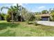 Image of the green home with a well-manicured lawn, mature trees, and a long driveway leading to the garage at 1200 Auger Dr, New Smyrna Beach, FL 32168