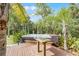 Outdoor hot tub with a custom wood deck surrounded by lush tropical landscaping and mature palm trees at 1200 Auger Dr, New Smyrna Beach, FL 32168