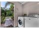 Bright laundry room with modern washer and dryer, leading to an outdoor patio with views of the tropical landscape at 1200 Auger Dr, New Smyrna Beach, FL 32168