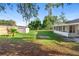 Spacious backyard featuring green grass, storage shed, lush trees, and a screened in lanai at 1550 Maxwell Ln, Deltona, FL 32738