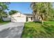 Charming single-Gathering home with an attached garage, light beige siding and well-manicured lawn and mature tree at 1550 Maxwell Ln, Deltona, FL 32738