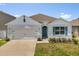 Charming single-story home featuring a two-car garage, teal door, manicured lawn and lovely landscaping at 1693 Barberry Dr, Kissimmee, FL 34744