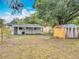 Wide angle shot of the backyard with several storage sheds, mature trees, and a small covered patio at 1913 S Summerlin Ave, Sanford, FL 32771
