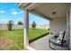 This covered back patio has two chairs and a view of the fenced-in backyard with lush green grass at 208 Summerlin Ln, Haines City, FL 33844