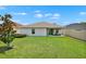A lovely backyard with a green lawn, a small tree and a covered patio with chairs at 208 Summerlin Ln, Haines City, FL 33844