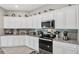 Bright kitchen features white cabinets, granite countertops, and stainless steel appliances at 208 Summerlin Ln, Haines City, FL 33844