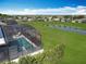 Aerial view of a screened in pool and spa, overlooking a large, green lawn, lake and neighborhood at 2312 Panoramic Cir, Apopka, FL 32703