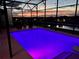 Enclosed, in-ground pool, lit with purple lights, and an evening view of the neighborhood at 2312 Panoramic Cir, Apopka, FL 32703