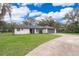Charming single-story home with a well-manicured lawn, gray roof, a paved driveway, and a two-car garage at 237 Church St, Lake Helen, FL 32744