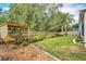 A backyard features a wooden fence, a patch of lush green grass, with a lattice arbor providing shade to the landscape at 249 Mill Slough Rd, Oviedo, FL 32766