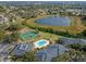 Scenic aerial view featuring a pool, tennis courts, lake, and community buildings surrounded by greenery at 2498 Saint Augustine Blvd, Haines City, FL 33844