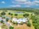 Aerial view of community clubhouse, pool, tennis courts, and lush landscaping near a beautiful lake at 3149 Songbird Cir, Harmony, FL 34773
