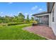 Lush backyard with a brick patio, manicured lawn, mature trees, and an enclosed screened-in porch at 3149 Songbird Cir, Harmony, FL 34773