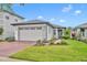 Charming single-Gathering home featuring a well-manicured lawn, gray paint, brick driveway, and two-car garage at 3149 Songbird Cir, Harmony, FL 34773