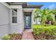 Close up of the front entrance with blue-green door, manicured landscaping, and a brick pathway at 3149 Songbird Cir, Harmony, FL 34773