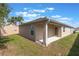 View of backyard and patio featuring lush green grass, blue skies, and mature landscaping at 490 Pentas Ln, Haines City, FL 33844