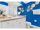 Modern bathroom with blue walls, decorative woven baskets, and a white vanity with gold knobs at 5300 S Atlantic Ave # 5507, New Smyrna Beach, FL 32169