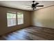 A sunlit bedroom with wood-look flooring, two windows, neutral walls, and an overhead fan at 56048 Blue Creek Rd, Astor, FL 32102