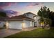Charming single-Gathering home with a well-manicured lawn, two car garage, and tropical landscaping against a colorful sunset sky at 5672 Parkview Lake Dr, Orlando, FL 32821