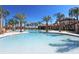 Stunning resort-style pool with palm trees, lounge chairs, and ample seating areas at 7224 Oakmoss Loop, Davenport, FL 33837