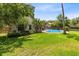 The large backyard features lush green grass, mature trees, landscaping, and a view of a sparkling pool at 7249 Abbey Ln, Winter Park, FL 32792